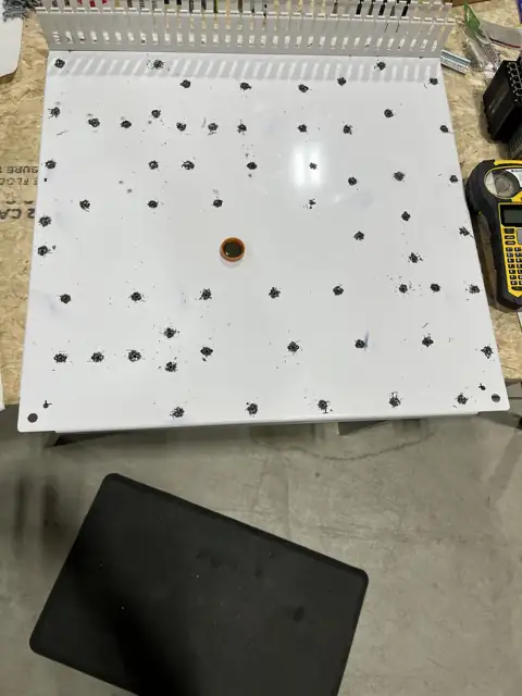 White control panel backpanel with dozens of drilled and tapped mounting holes, wire duct along the top edge, and a label printer beside it